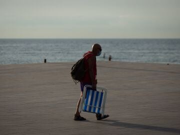 Un ciudadano se dirige hacia la playa de la Barceloneta en Barcelona, vacía de turistas. EFE/ Enric Fontcuberta