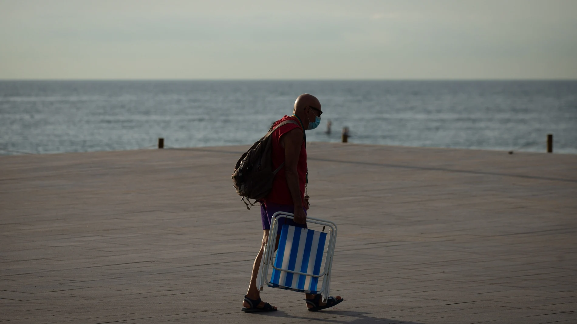 Un ciudadano se dirige hacia la playa de la Barceloneta en Barcelona, vacía de turistas. EFE/ Enric Fontcuberta