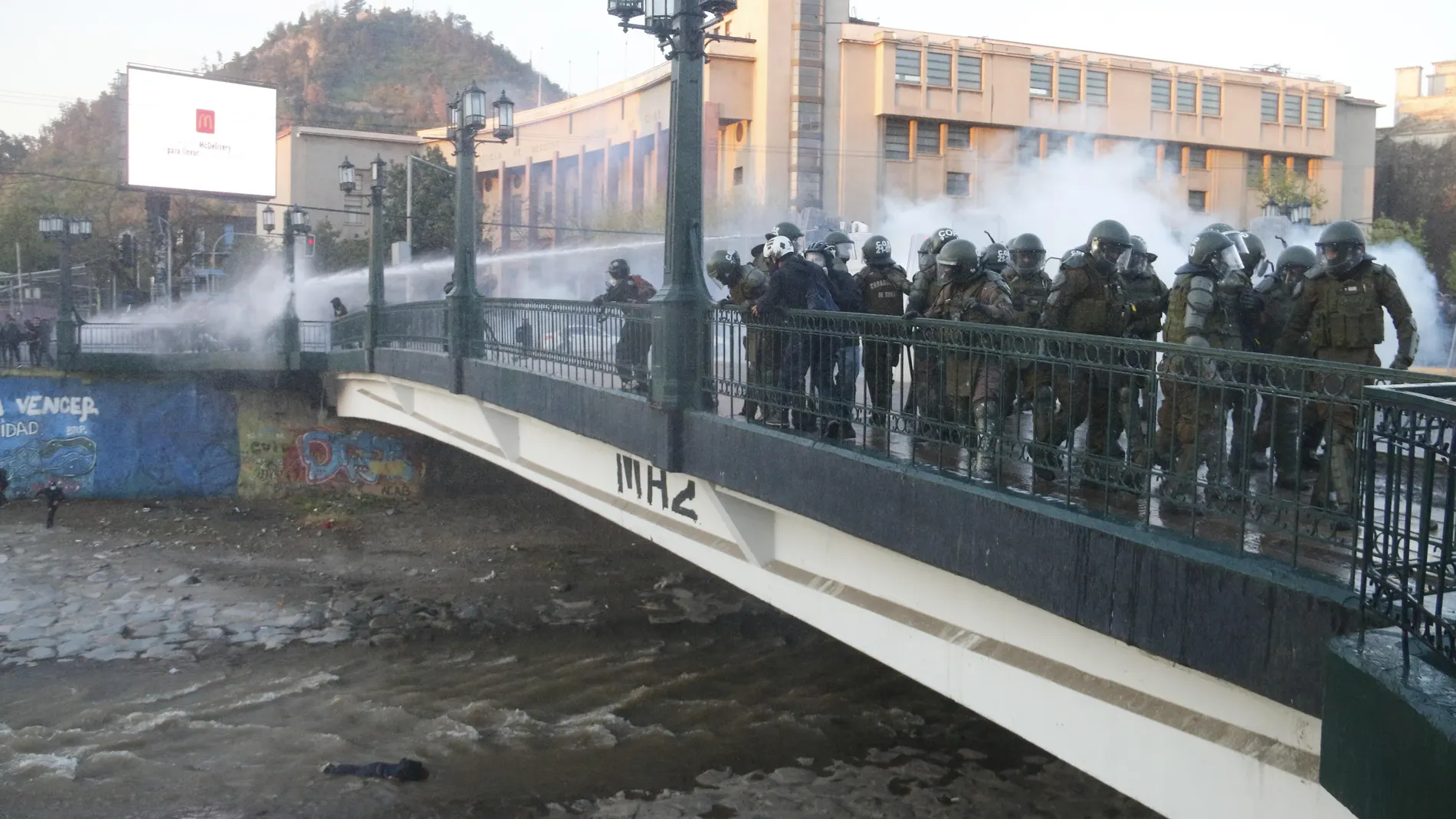 Los carabineros observan a un manifestante que se encuentra inconsciente tras caer al río Mapocho, en Santiago (Chile)