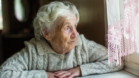 Imagen de una persona de la tercera edad mirando por la ventana