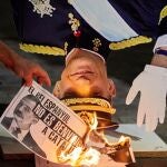 Varias personas participan en la quema popular de fotos del rey durante el acto organizado por la ANC en la víspera de la visita de Felipe VI a Barcelona, este jueves en Gerona. EFE/David Borrat.