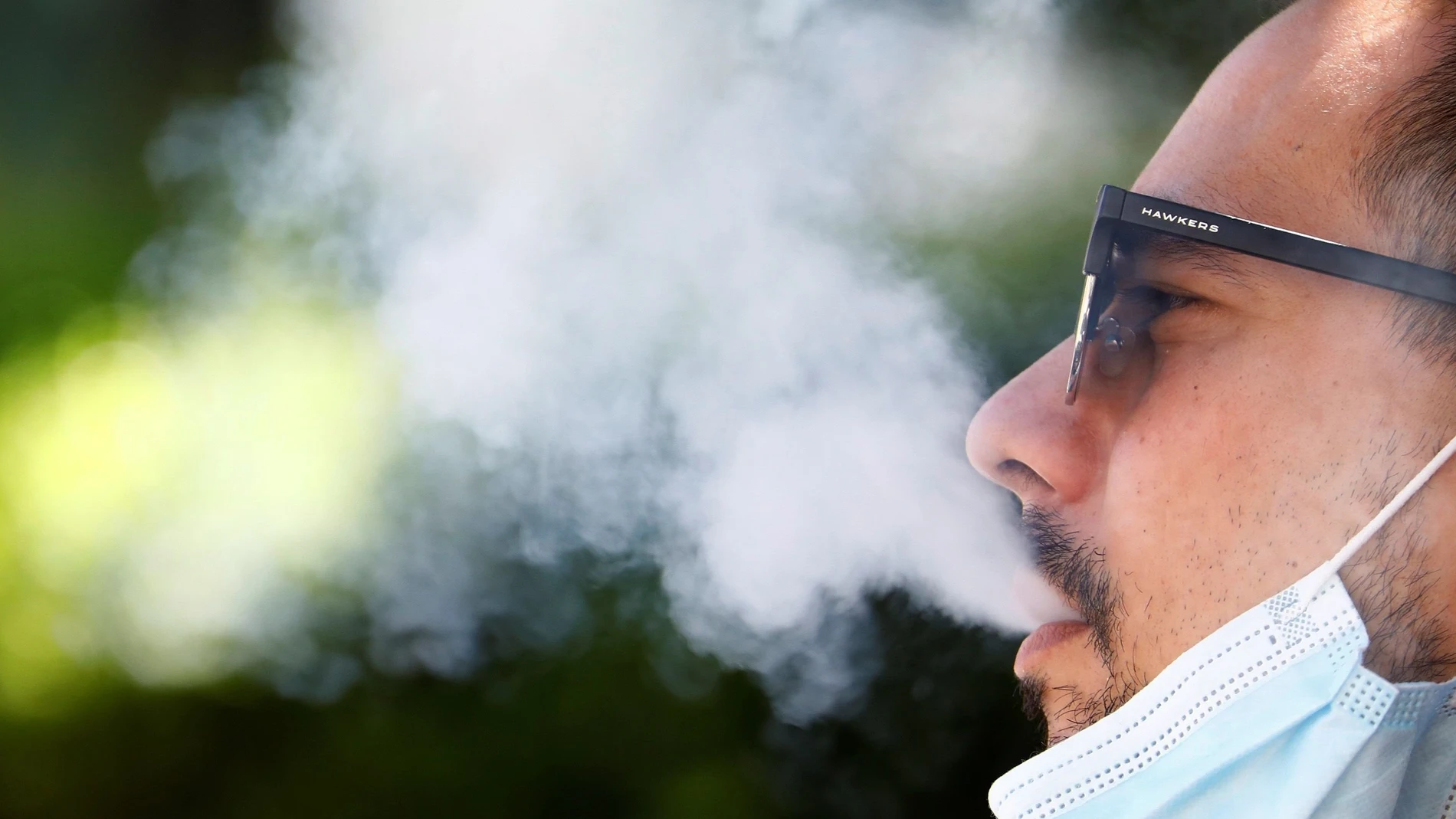 Un hombre expulsa el humo del tabaco mientras fuma sentado en una calle en Córdoba. EFE/Salas
