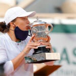 Ina Swiatek besa, después de haberse bajado la mascarilla, el trofeo de campeona de Roland Garros