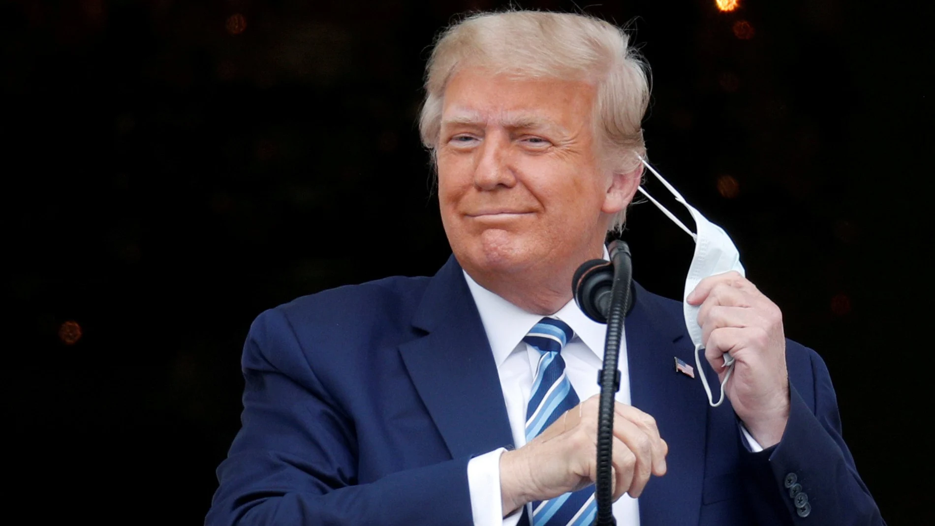 El presidente Donald Trump se quita la mascarilla al salir el sábado al balcón de la Casa Blanca