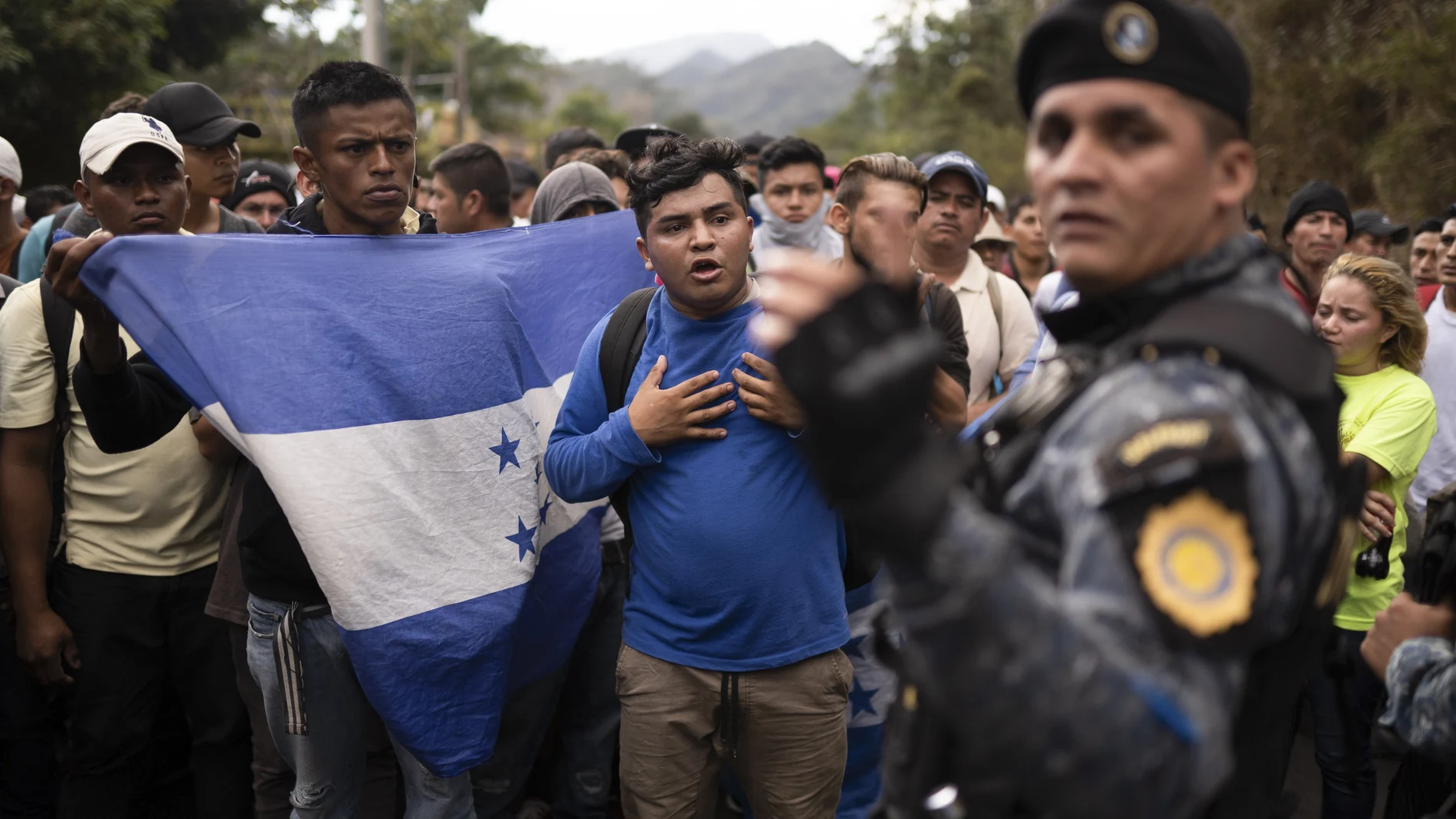 FILE - In this Jan. 16, 2020 file photo, Honduran migrants walking in a group stop before Guatemalan police near Agua Caliente, Guatemala, on the border with Honduras. In a report released Tuesday, Oct. 13, 2020, by the Democratic staff of a U.S. Senate committee says U.S. immigration agents assigned to Guatemala to advise local authorities violated terms of their funding by helping officials deport Hondurans traveling in a migrant caravan early this year. (AP Photo/Santiago Billy, File)