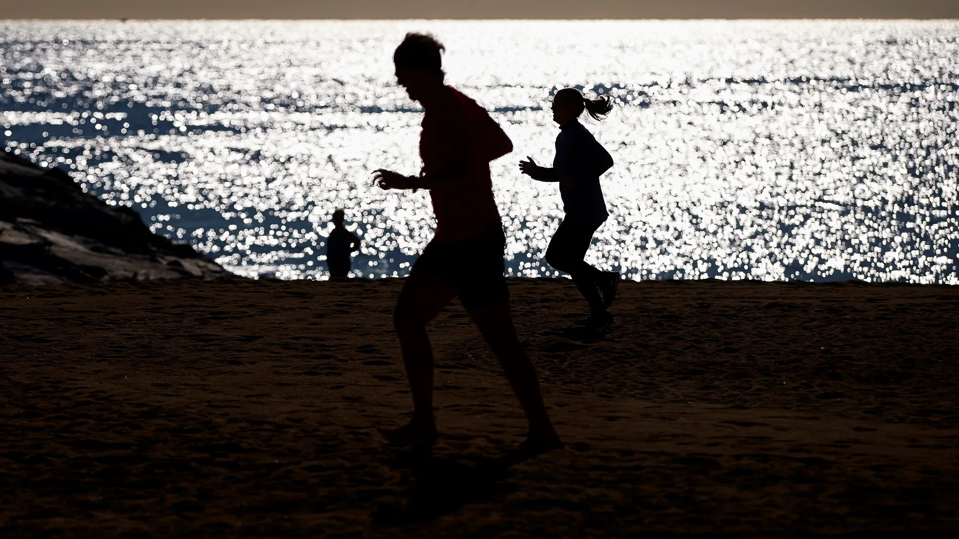 Varias personas practican deporte en la playa de la Barceloneta