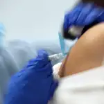 Una enfermera pone la vacuna de la gripe a un señora