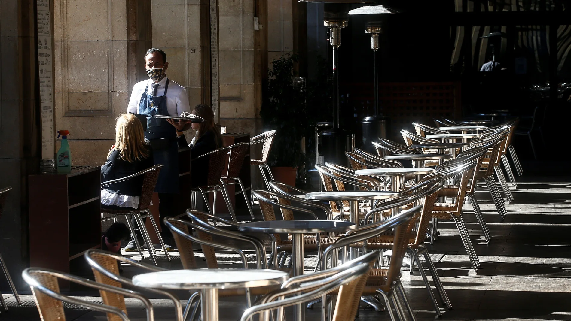 Un camarero atiende a un cliente, este miércoles, en un local de la Plaza Real de Barcelona, tras la decisión del Govern de cerrar bares y restaurantes en Cataluña durante 15 días.