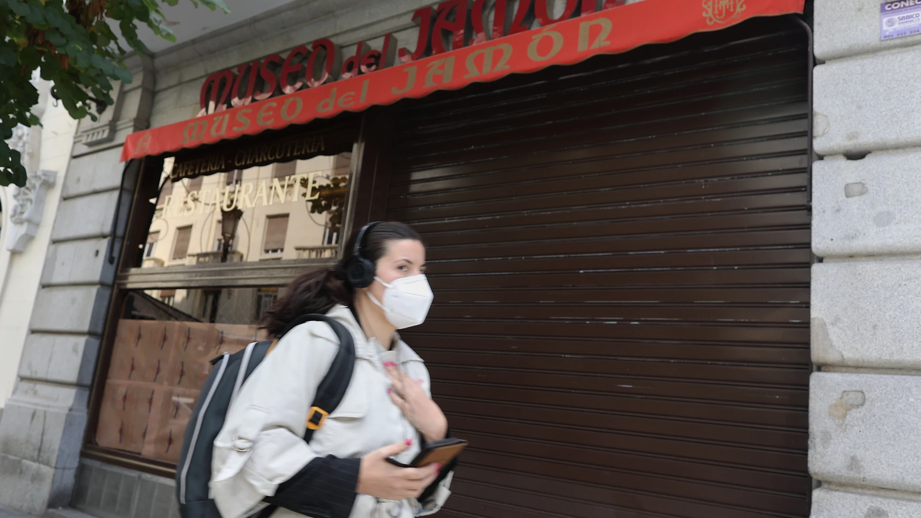 Una mujer pasa por el establecimiento cerrado del Museo del Jamón en la calle Mayor, 7, en Madrid (España)