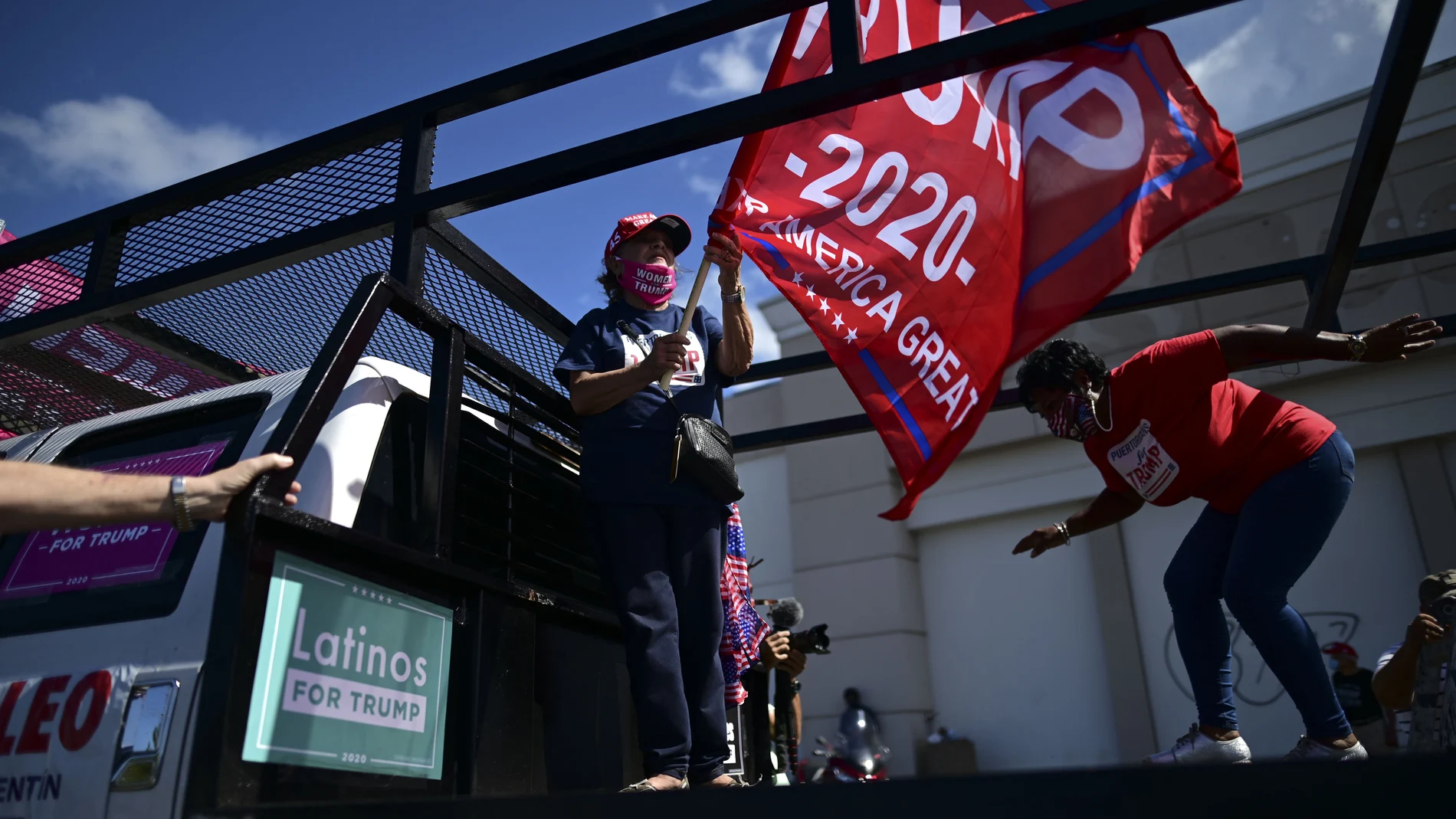 Former senator Miriam RamÃ­rez de Ferrer carries a pro-Trump flag moments before leaving for the headquarters of the Republican party in support of President Donald Trump's candidacy a few weeks before the presidential election next November, in Carolina, Puerto Rico, Sunday, Oct. 18, 2020. President Donald Trump and former Vice President Joe Biden are targeting Puerto Rico in a way never seen before to gather the attention of tens of thousands of potential voters in the battleground state of Florida. (AP Photo/Carlos Giusti)
