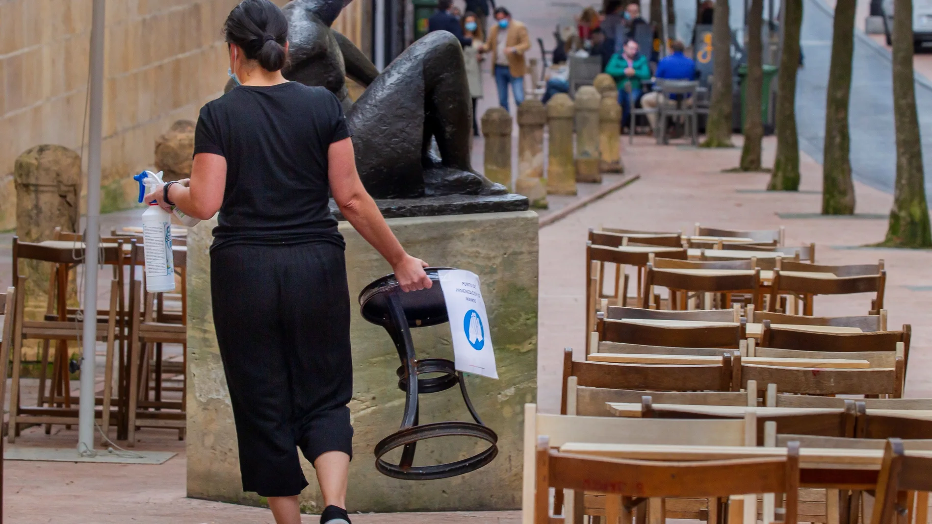 Una mujer desinfecta un asiento de una terraza del centro de Oviedo este lunes. Asturias sumó ayer 269 casos positivos de coronavirus durante una jornada, la cifra más alta registrada en el Principado desde que comenzó la pandemia