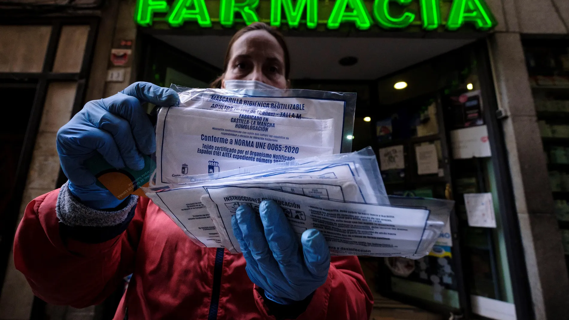 Entrega de mascarillas quirúrgicas a la entrada de una farmacia de Toledo