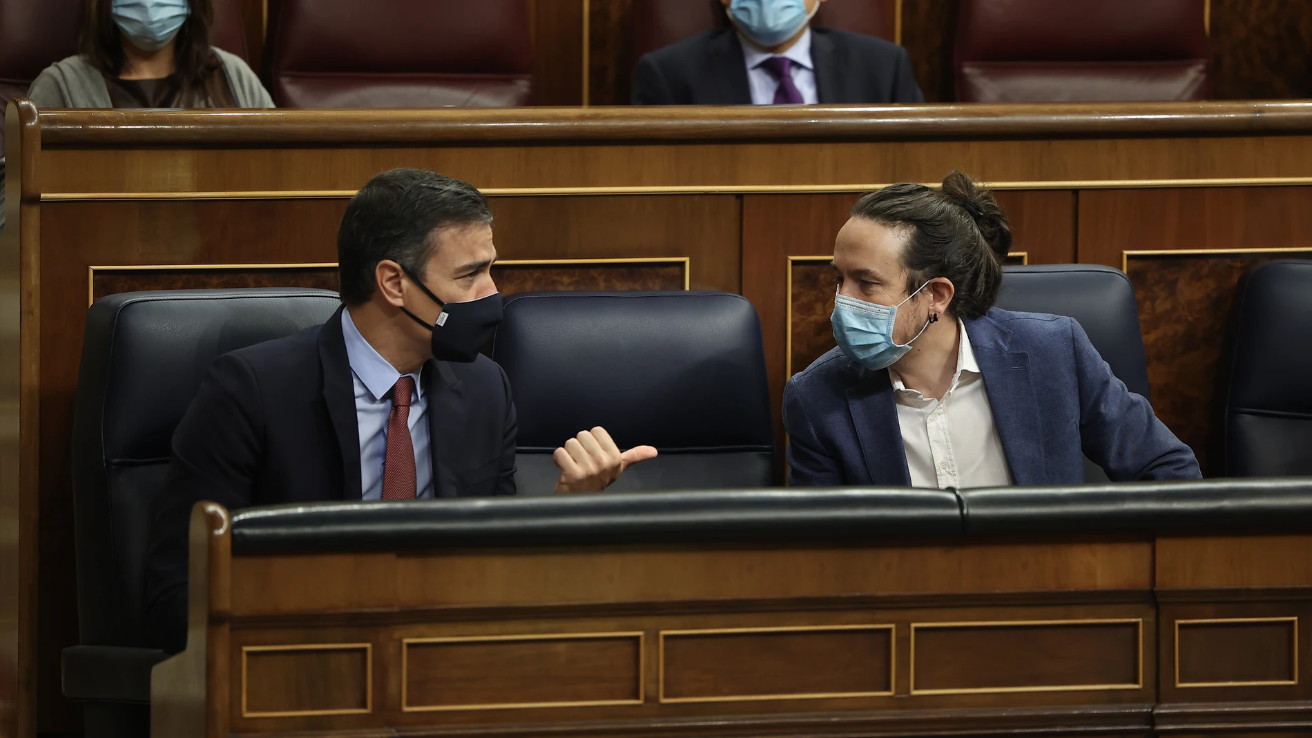 El presidente del Gobierno, Pedro Sánchez (i); y el vicepresidente segundo del Gobierno, Pablo Iglesias, mantienen una conversación durante el pleno en el que se debate la moción de censura planteada por Vox, en el Congreso de los Diputados