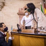 El presidente de la Junta de Andalucía, Juanma Moreno (i), saluda a la presidenta del Parlamento, Marta Bosquet (d), que ha vuelto tras superar el Covid-19, durante la segunda jornada del Debate sobre el Estado de la Comunidad en el Parlamento de Andalucía