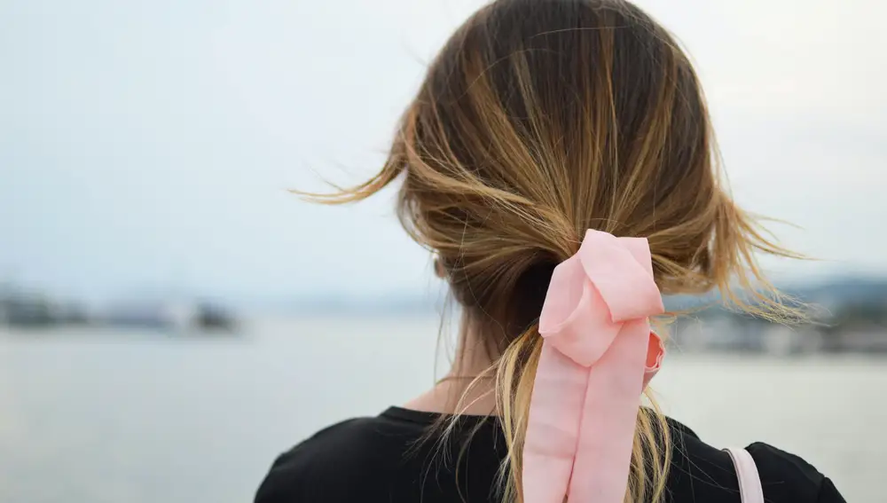 En la imagen, una chica con lazo rosa en el pelo.