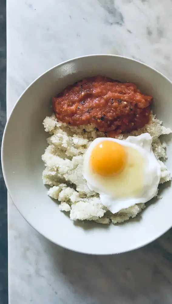 En la imagen, un plato de falso arroz de coliflor con tomate casero y huevo frito al agua.