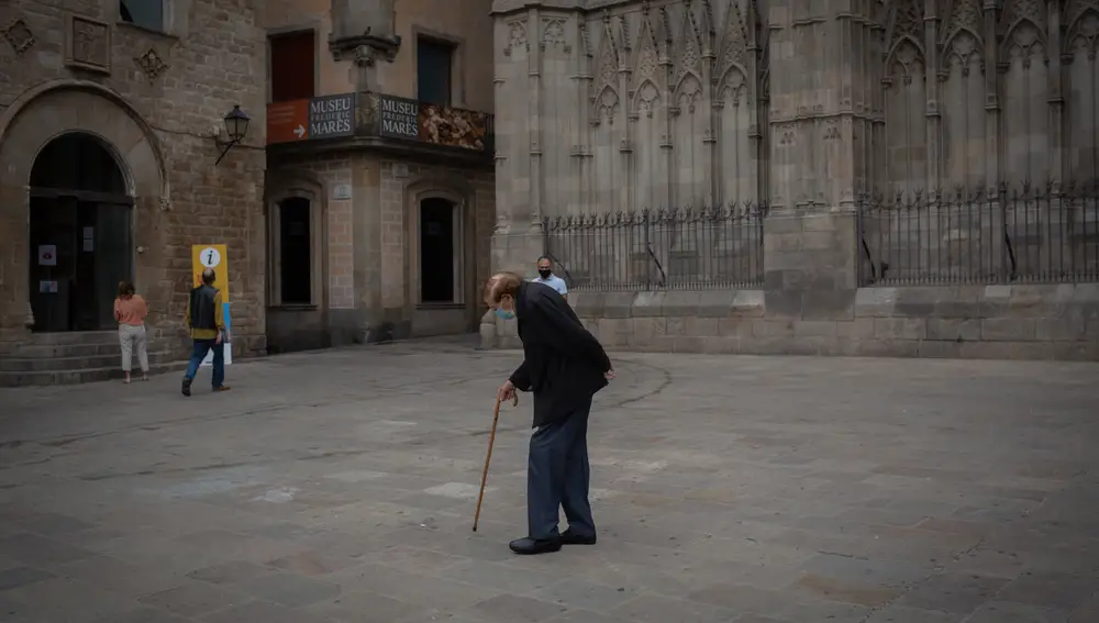Un anciano camina por una plaza del Barrio Gótico de Barcelona