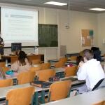 Una profesora explica en un aula con enseñanza mixta, presencial y telemática