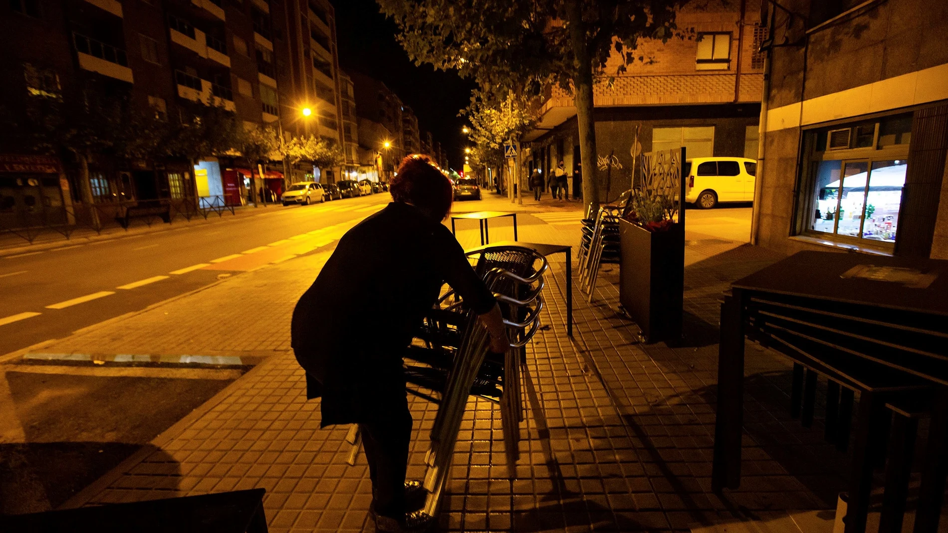 La dueña de un bar recoge la terraza minutos antes de las 22.00 hoy sábado en Aranda de Duero, tras el toque de queda decretado por el Gobierno de Castilla y León.