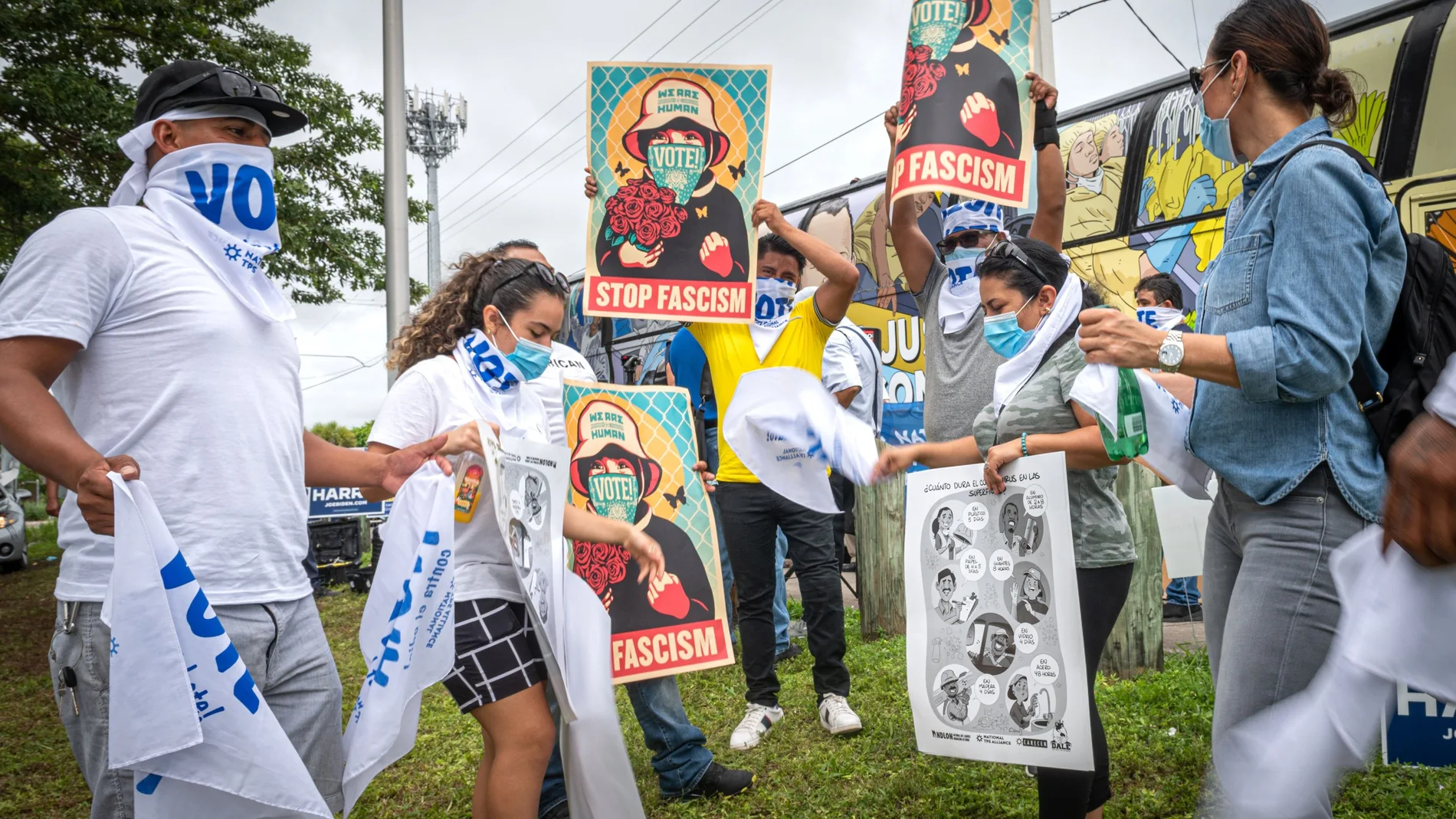 Beneficiarios del Estatus de Protección Temporal (TPS) sostienen pancartas que dicen "Stop Fascism" (Basta de fascismo) a la llegada del autobús "La libertad" y rodeados de carteles electorales, en Miami, Florida (EEUU).
