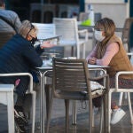 Dos personas con mascarilla en una terraza de Málaga