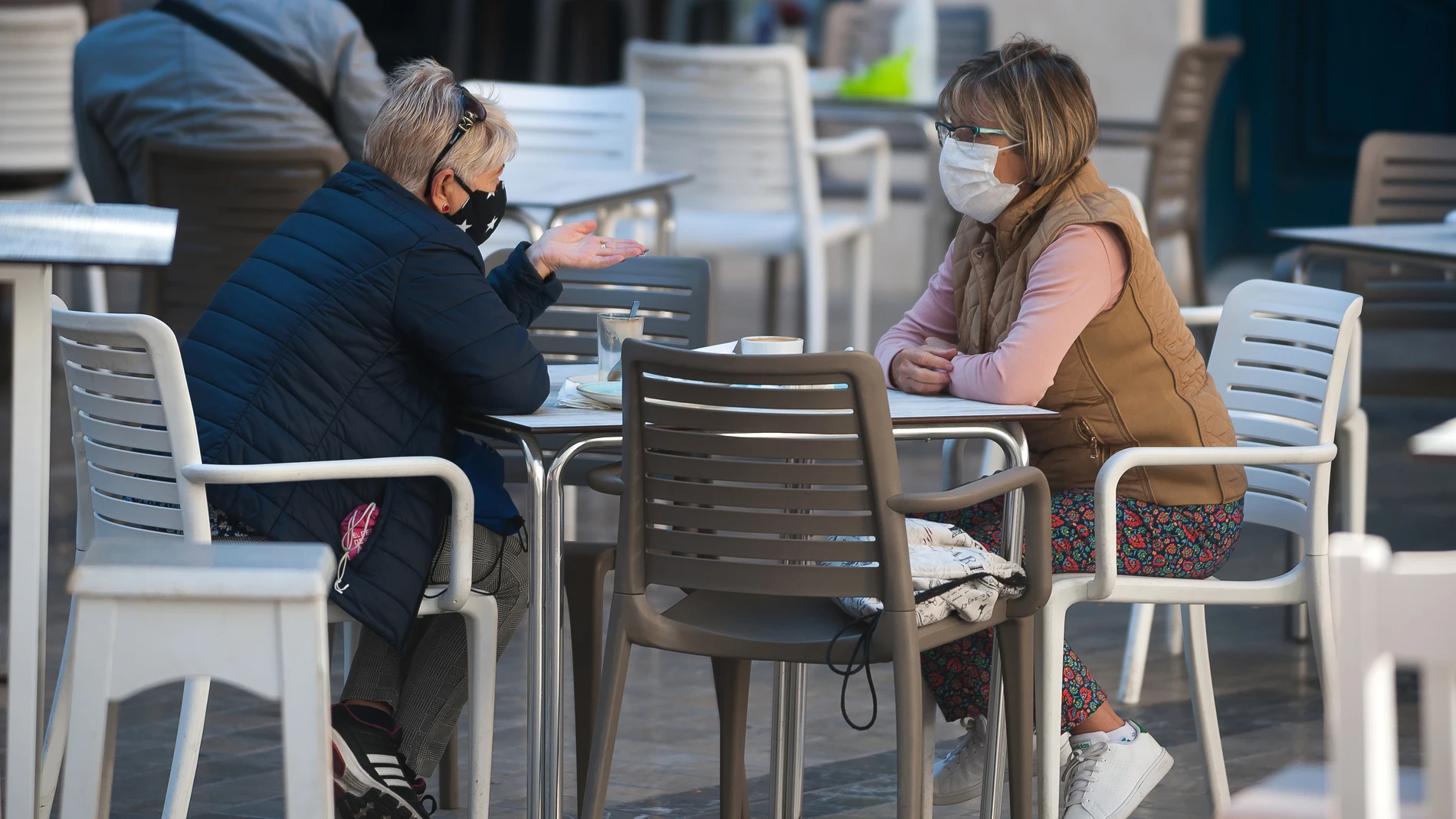 Dos personas con mascarilla en una terraza de Málaga