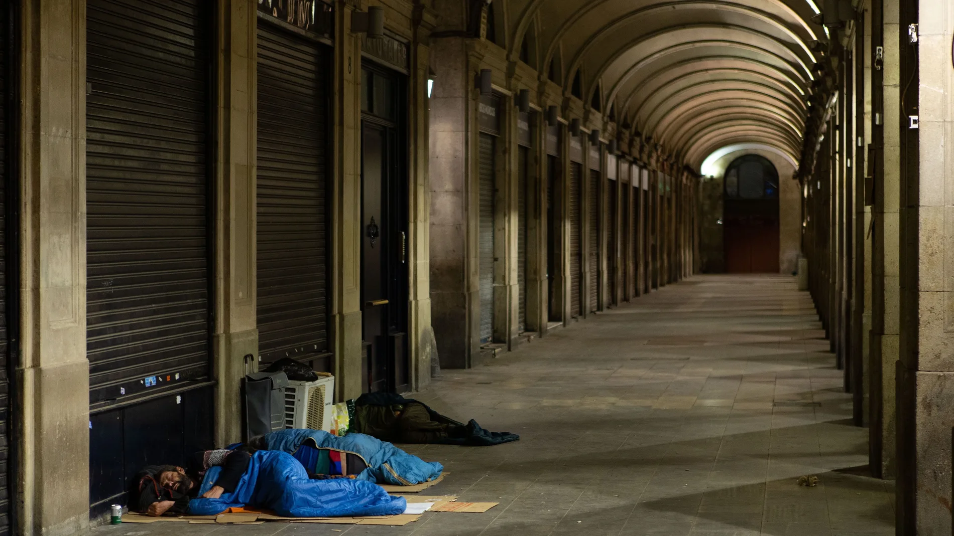 Personas sin hogar duermen en la Plaza Real de Barcelona