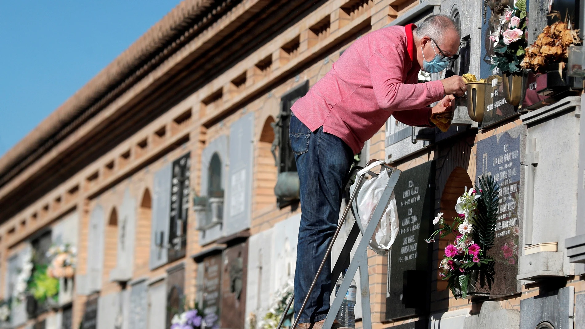 Una persona limpia una lápida en el Cementerio General de Valencia