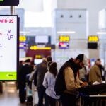 Imagen de archivo de una pantalla que informa sobre la distancia a mantener entre personas frente a una cola de embarque en el aeropuerto Costa del Sol en Málaga