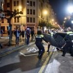 Miembros de la Policía Municipal retiran los contenedores volcados en la calzada por los participantes en las protestas en las calles de Bilbao