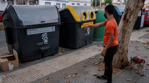 Un hombre ante el contenedor de basura de Huelva donde se ha hallado una bolsa de basura con restos humanos