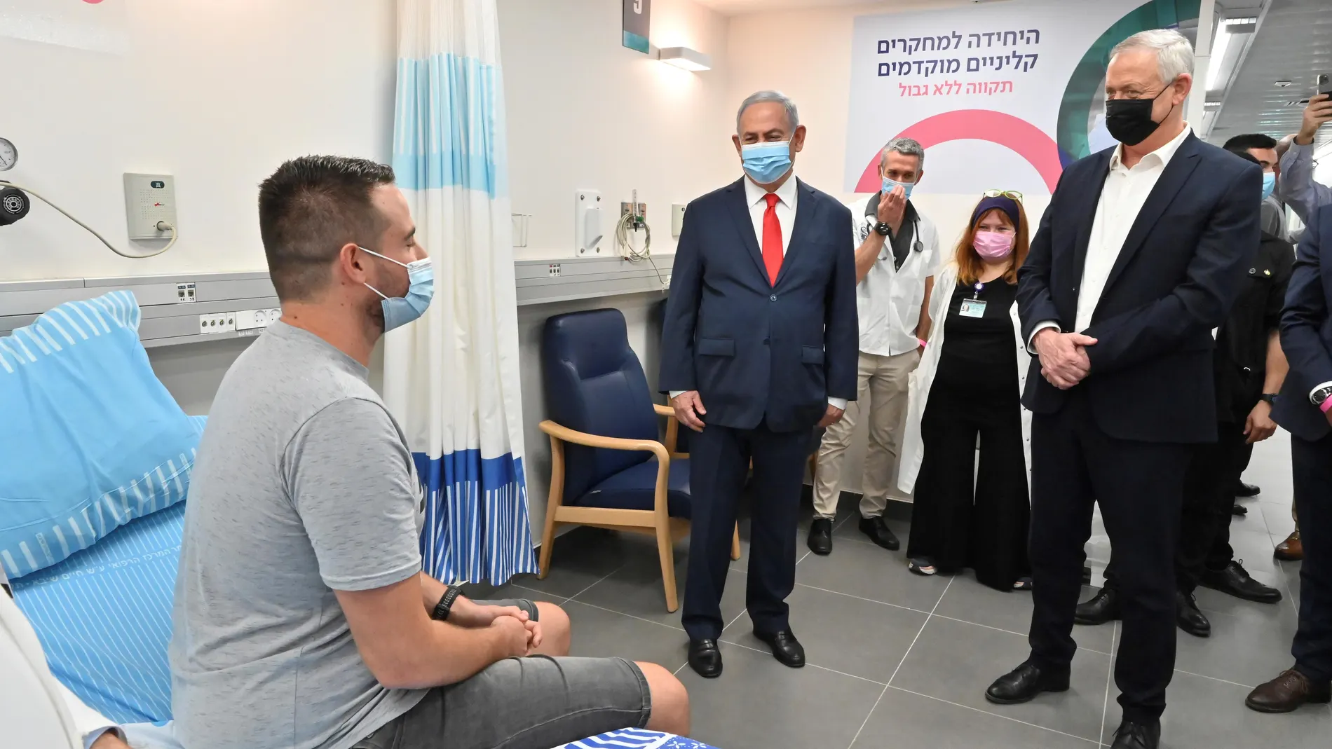 El ministro de Defensa israelí, Benny Gantz (d) junto al primer ministro Benjamín Netanyahu, con uno de los vacunados