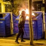 Un agente de la policía junto al contenedor de papel que arde durante los nuevos incidentes registrados hoy en Logroño tras los disturbios de anoche, en los que cerca de 150 radicales quemaron contenedores, cortaron varias calzadas, saquearon un comercio y tiraron piedras, bengalas y otros objetos a la policía.