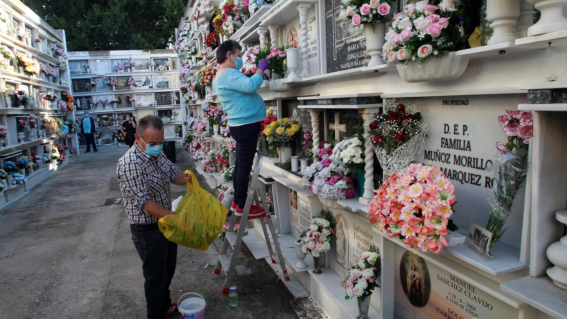 Los familiares colocan flores en las lápidas de las tumbas de sus fallecidos en el cementerio de Algeciras