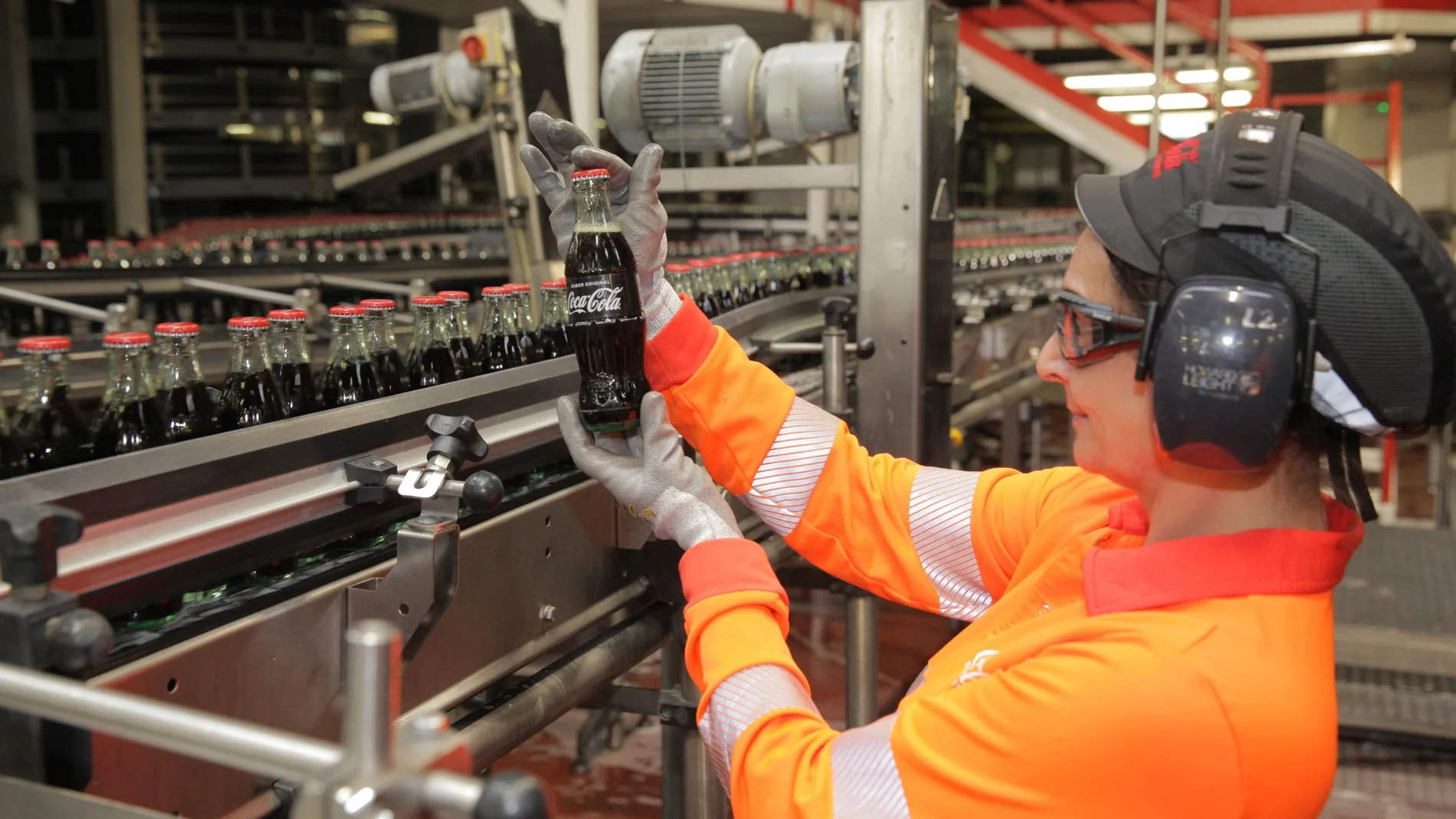 Una empleada examina una bebida en una línea de producción