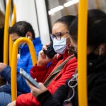 Una mujer con mascarilla habla por teléfono en el Metro de Madrid