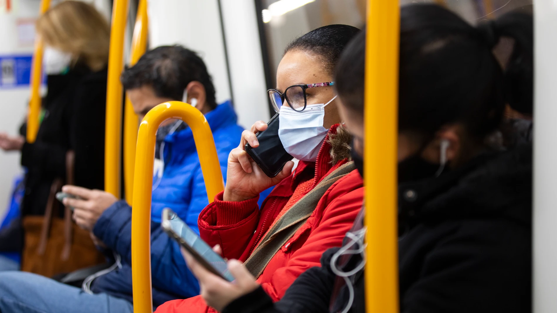Una mujer con mascarilla habla por teléfono en el Metro de Madrid