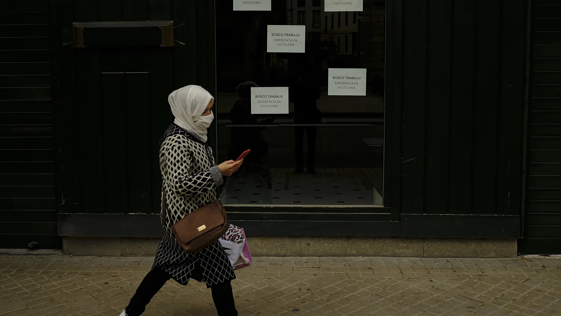 Una mujer camina con una mascarilla por el casco de Pamplona