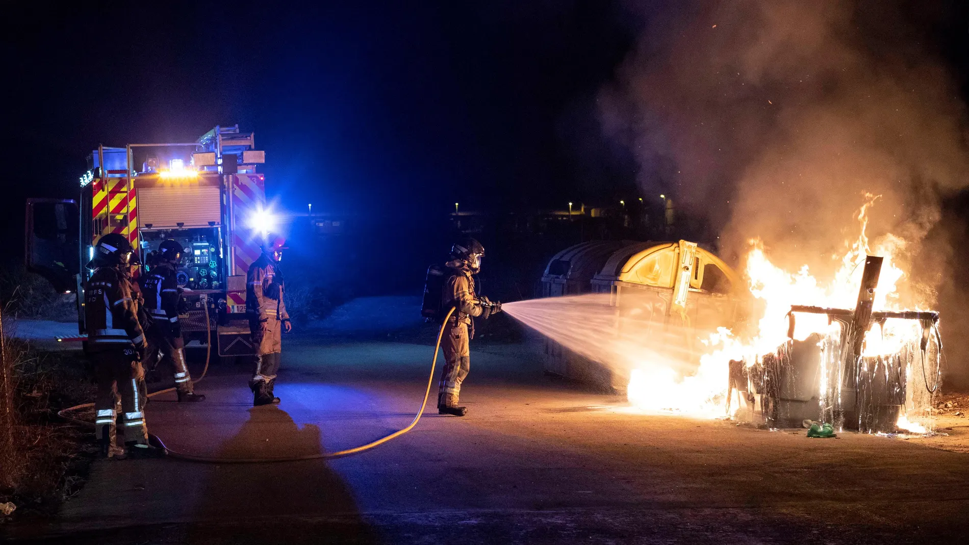 Bomberos sofocan el incendio de un contenedor de ropa que afecto al coche contiguo, esta pasada madrugada en la calle Madre Elisea Oliver de Murcia. La policía local detuvo a tres personas por pegar fuego a cinco contenedores en varias partes de la ciudad