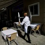 Un camarero recoge una mesa en un restaurante del barrio de la Barceloneta de Barcelona