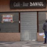 Vecinos leen los carteles de protesta colocados por un hostelero a las puertas de su negocio cerrado en Salamanca EFE/ JM Garcia