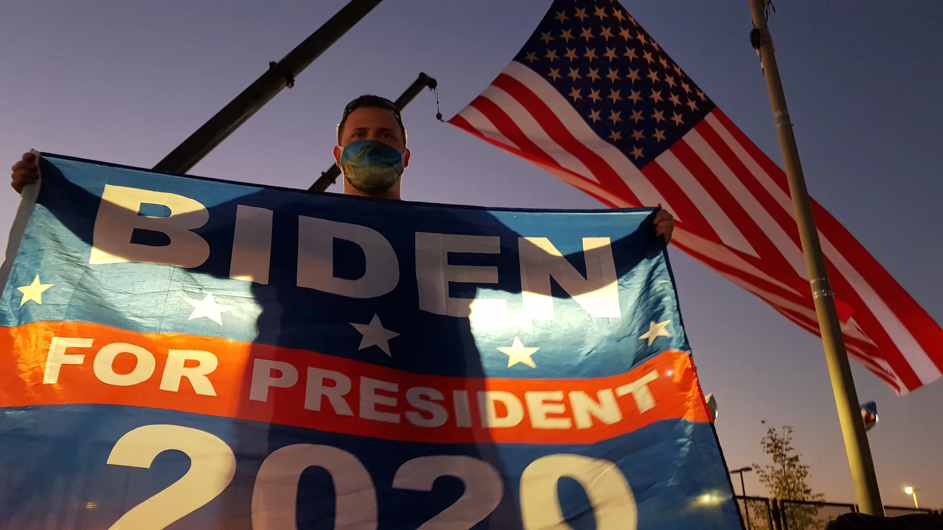 Un joven sostiene un banderín electoral de Joe Biden para presidente 2020 mientras espera su llegada para ofrecer el discurso de victoria