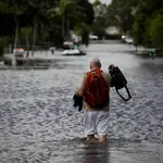 Un hombre camina por las inundaciones causadas por la tormenta tropical ETA en Davie, Florida