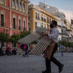 Un hostelero recoge el mobiliario de la terraza de un bar en Sevilla