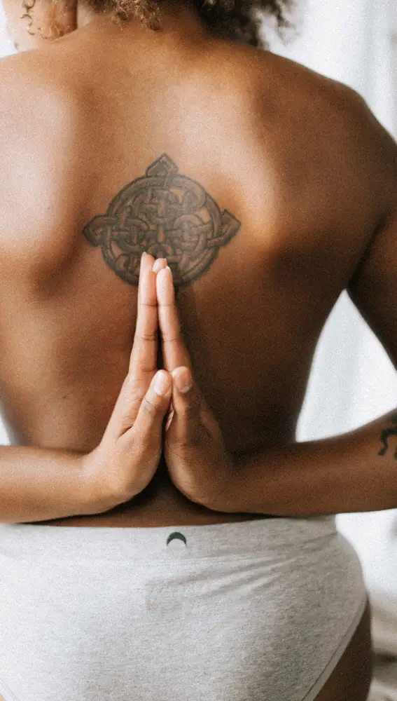En la imagen, una mujer practica yoga y nos muestra su tatuaje
