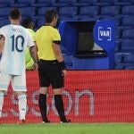 Leo Messi observa la pantalla del VAR detrás del árbitro Raphael Claus.