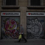Un hombre camina al lado de dos tiendas turísticas en Barcelona, Cataluña (España)