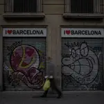Un hombre camina al lado de dos tiendas turísticas en Barcelona, Cataluña (España)