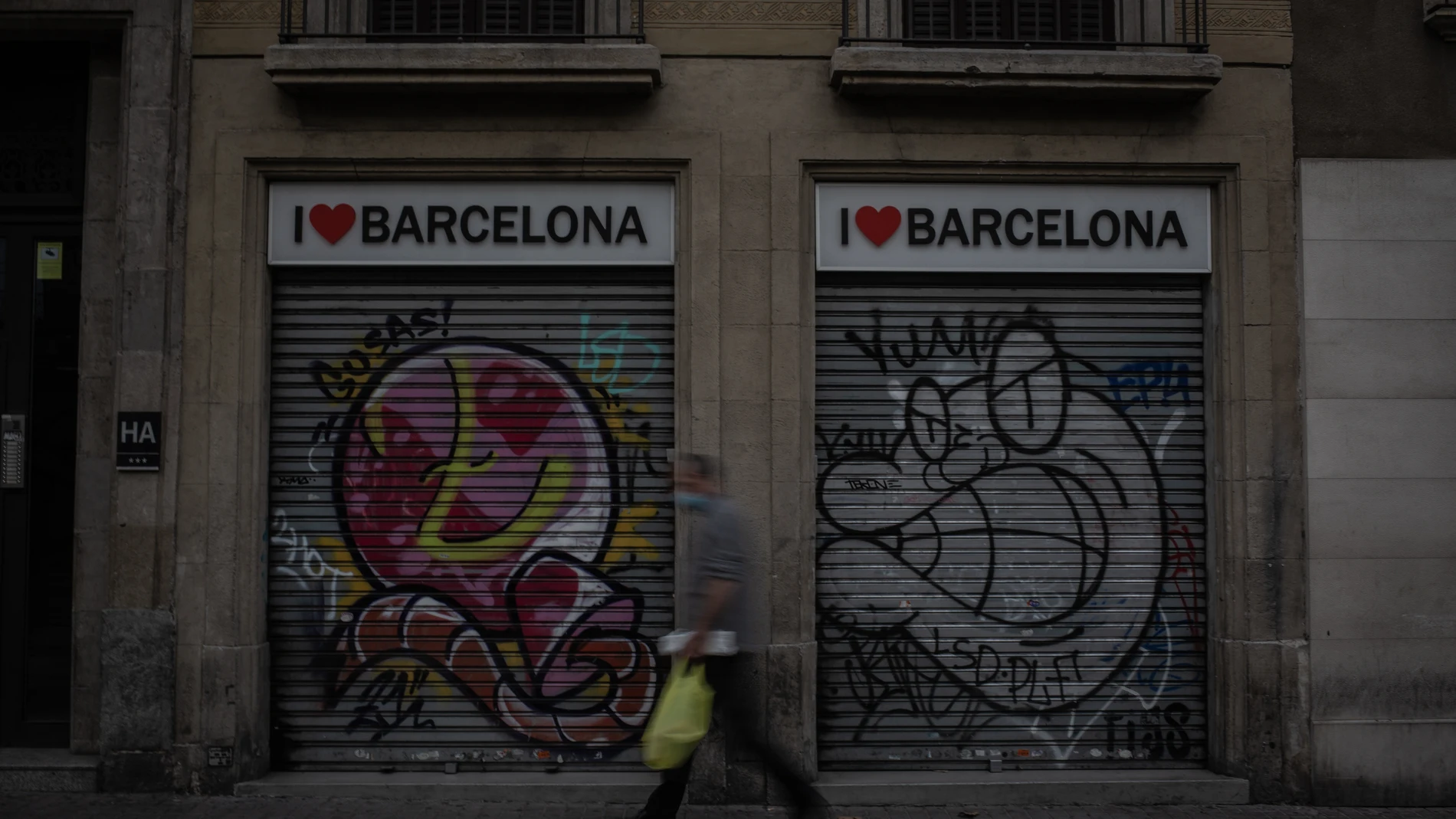Un hombre camina al lado de dos tiendas turísticas en Barcelona, Cataluña (España)