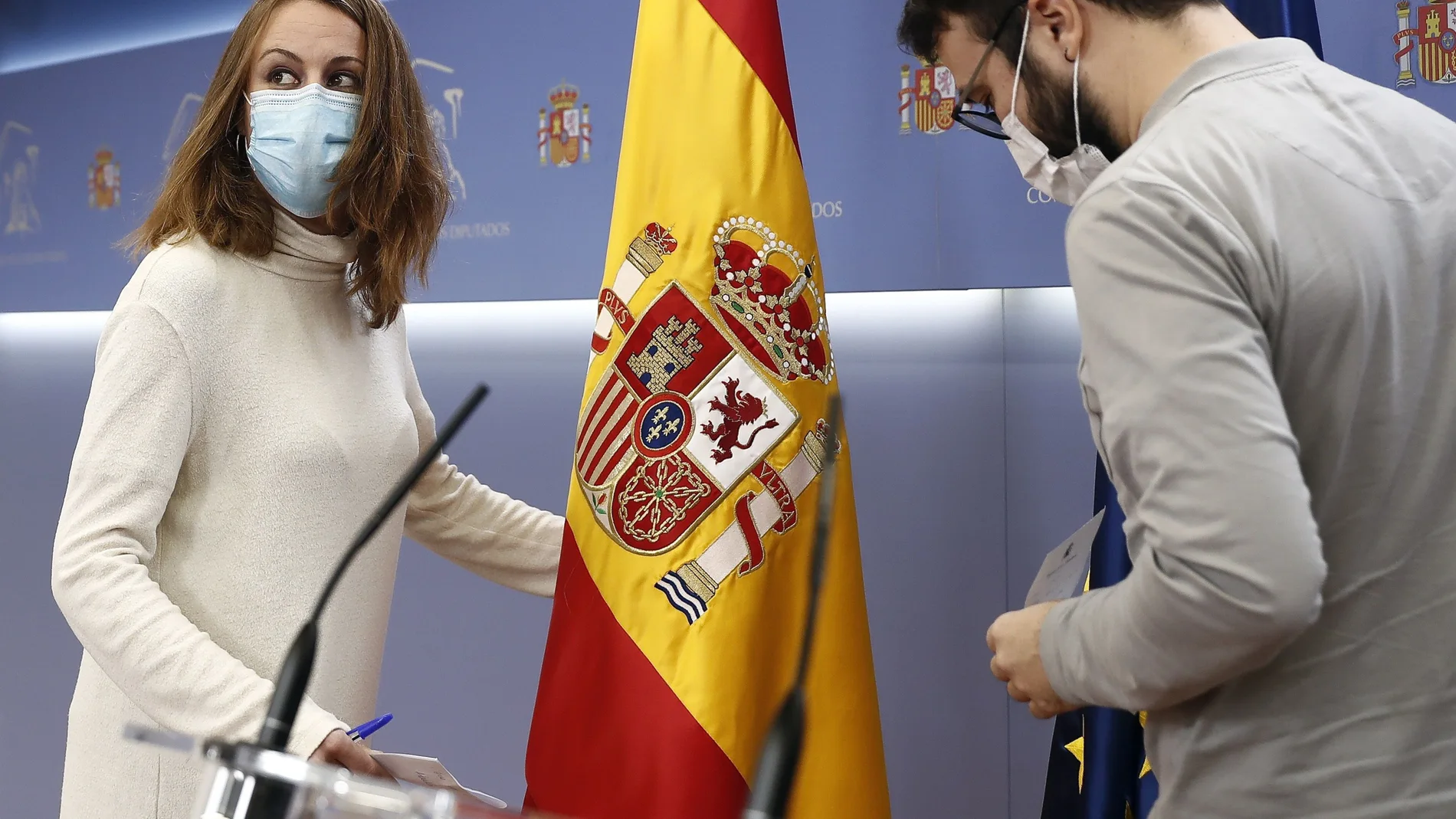 La portavoz de la CUP, Mireia Vehí (i) y su compañero de partido Albert Botran (d) retiran la bandera española durante la rueda de prensa tras la Junta de Portavoces del Congreso celebrada este martes